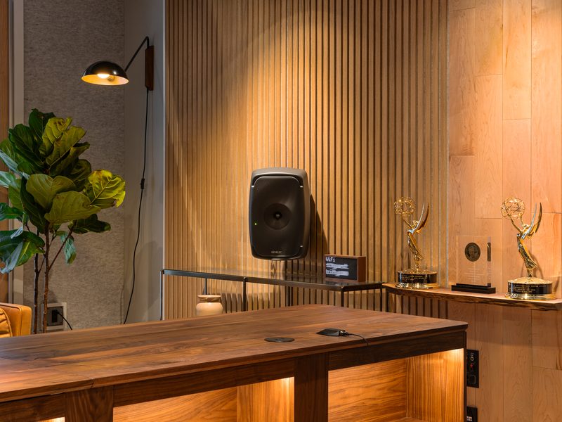 Wood-slat wall with a wall-mounted main monitor and award shelf